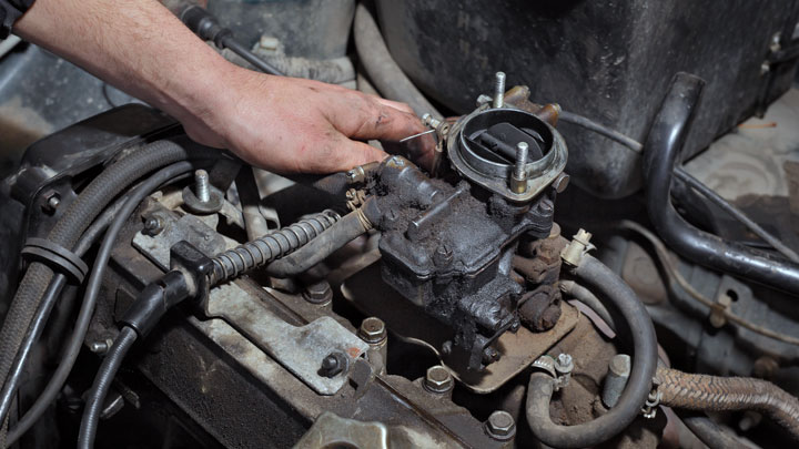 A Mechanic adjusting the carburetor of an old Toyota forklift